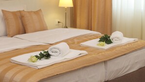 A hotel room with two beds, each with a rolled white towel and a yellow rose. - Booking Rooms (Belgrade)