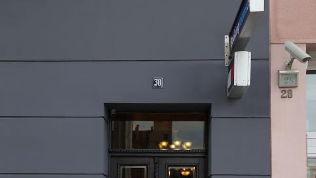 A black double door with a number 30 sign above it, flanked by two white planters with coniferous trees. - Booking Rooms (Belgrade)