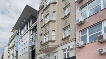 Un immeuble à plusieurs étages doté d’une façade moderne, d’un magasin Tommy Hilfiger et d’une enseigne Booking.com.