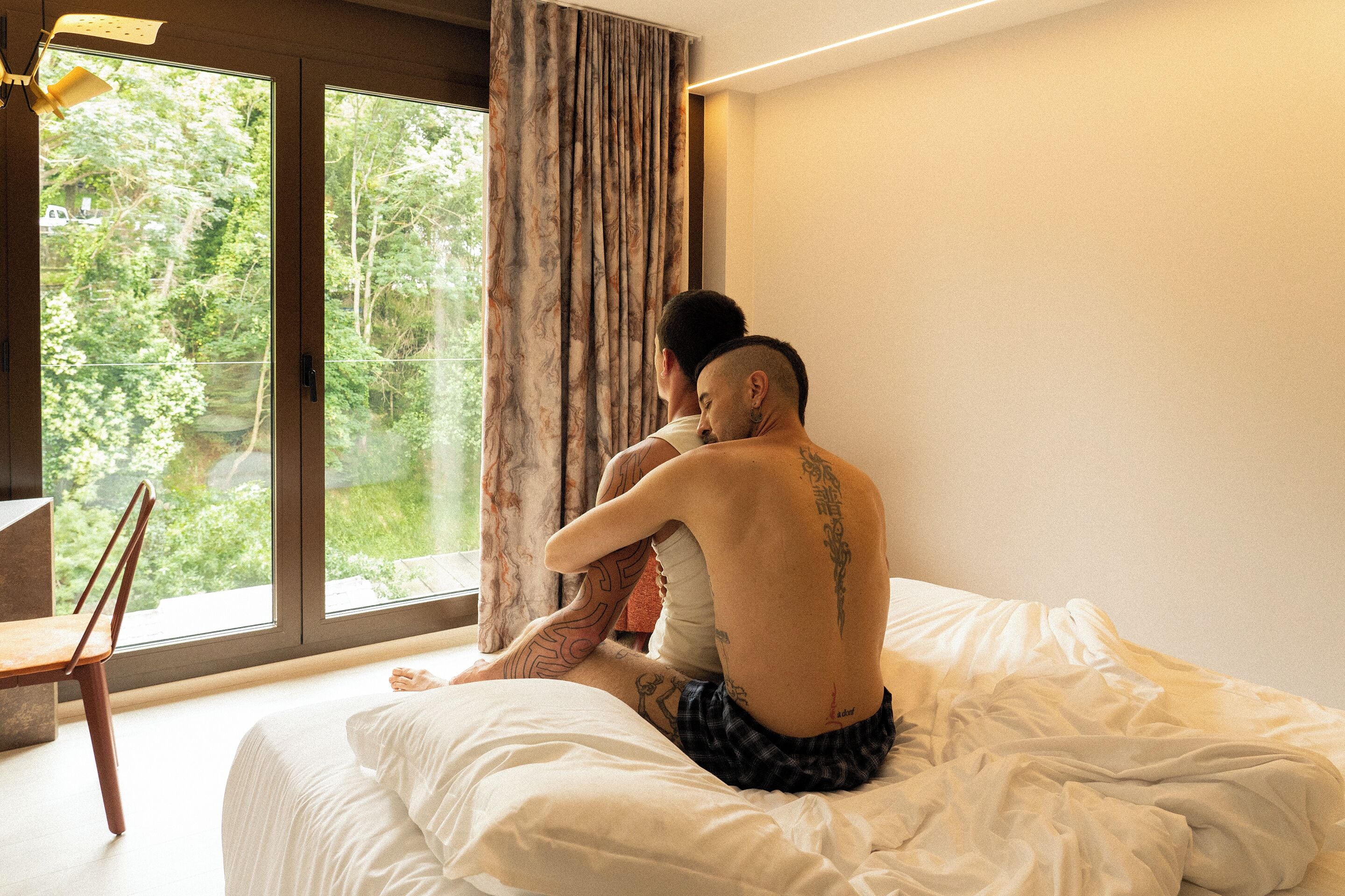 A bedroom with a large window, a bed, and a chair.