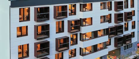A multi-story hotel with a modern design, featuring balconies, large windows, and a ground-level restaurant.