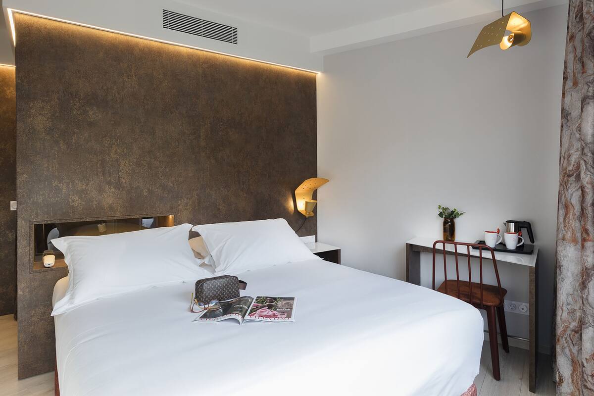 A modern hotel room with a large bed, a desk, and a chair.