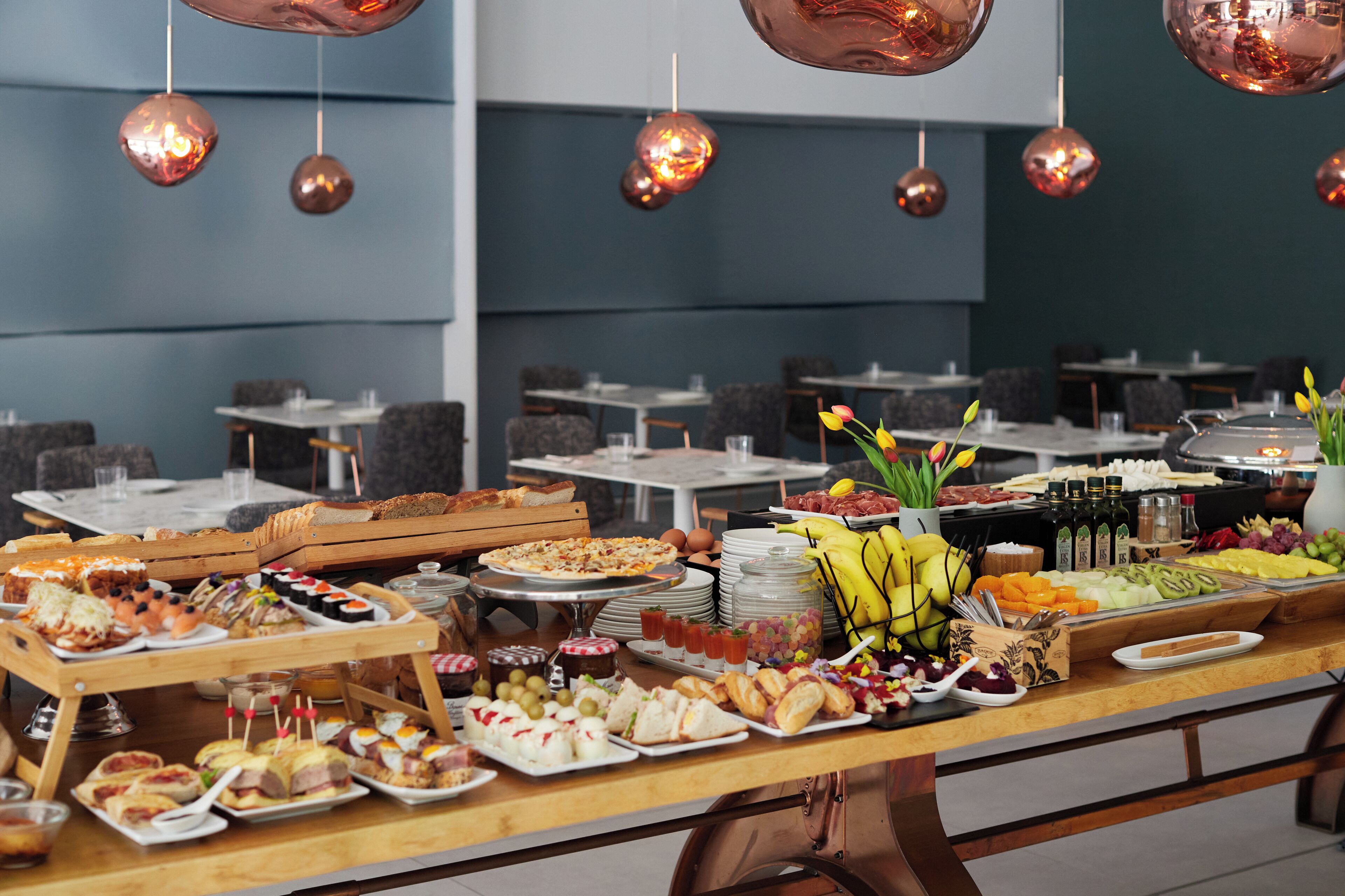 Een buffet met diverse gerechten en een zithoek met tafels en stoelen.