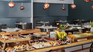 A buffet with various food items and a seating area with tables and chairs.