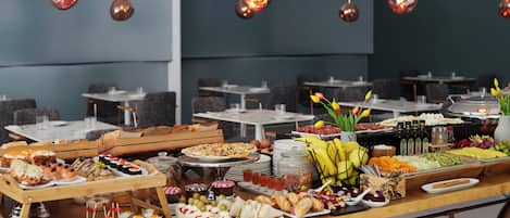 A buffet with various food items and a seating area with tables and chairs.