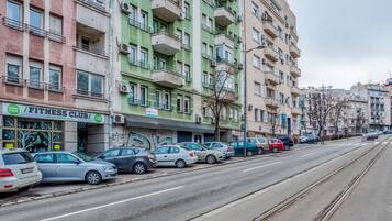 Fila de coches aparcados a lo largo de una calle con una vía de tranvía.