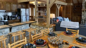 L’intérieur d’un chalet rustique comprenant une cuisine, un coin repas et un espace de vie.