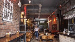 A restaurant interior with brick walls, wooden tables, and hanging lights. - Higgihaus at Hampton Whole House 6 Bed (Bristol)