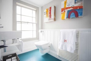 A bathroom with a toilet, a window, a radiator, and a towel rack.