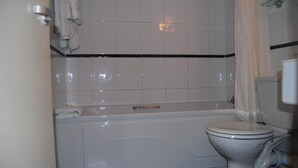 Une salle de bain avec une baignoire, des toilettes et un rideau de douche.