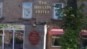 L’hôtel Brecon se distingue par sa façade en briques, sa grande fenêtre et une enseigne indiquant son nom.