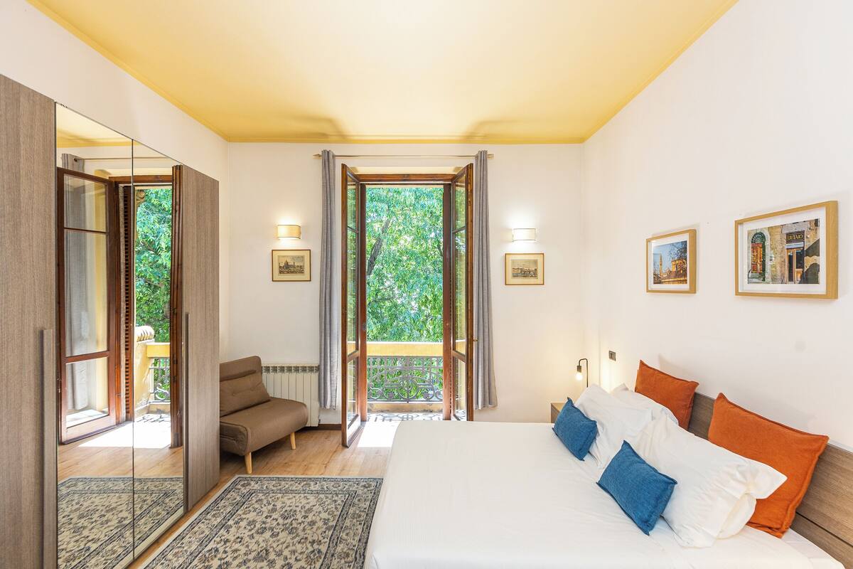 Une chambre dotée d’un grand lit, d’un canapé, d’un balcon avec vue et d’une porte donnant sur l’extérieur.