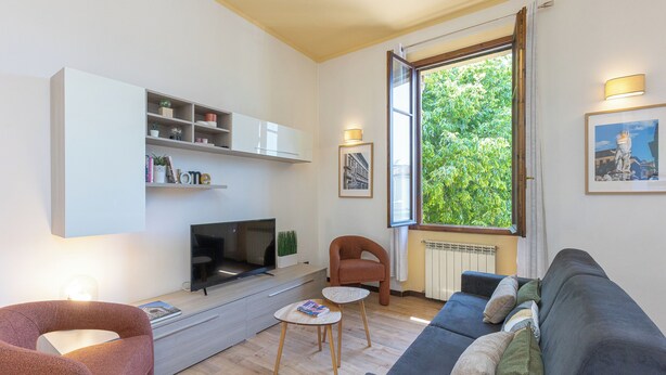 Un salon moderne avec un canapé, un fauteuil, une télévision et une bibliothèque.
