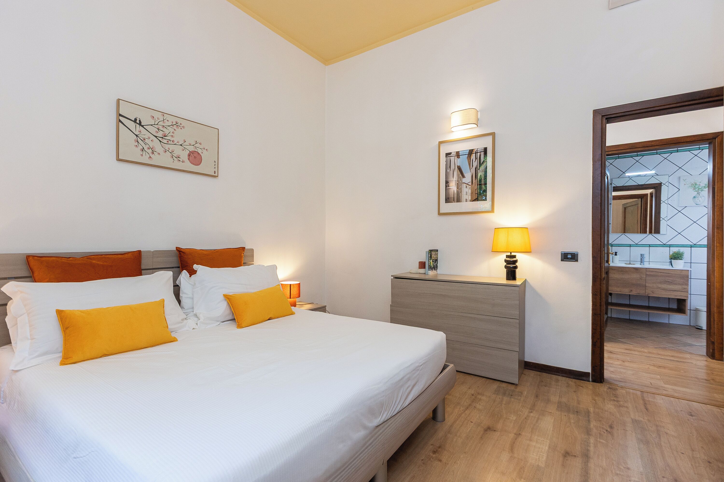 Un dormitorio con cama, mesitas de noche, cómoda y espejo.