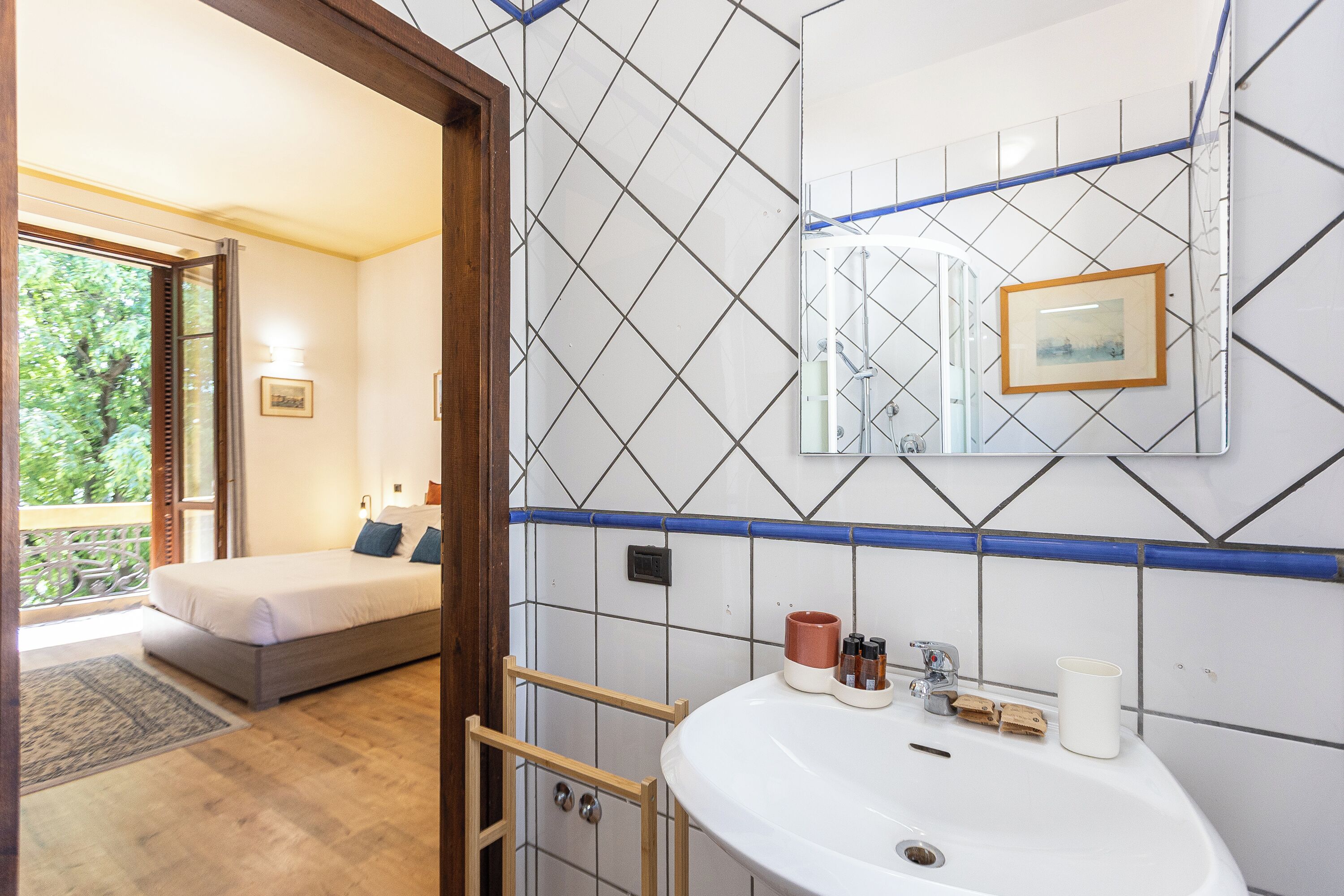 Ein Schlafzimmer mit Bett, ein Badezimmer mit Waschbecken und Blick ins Freie.