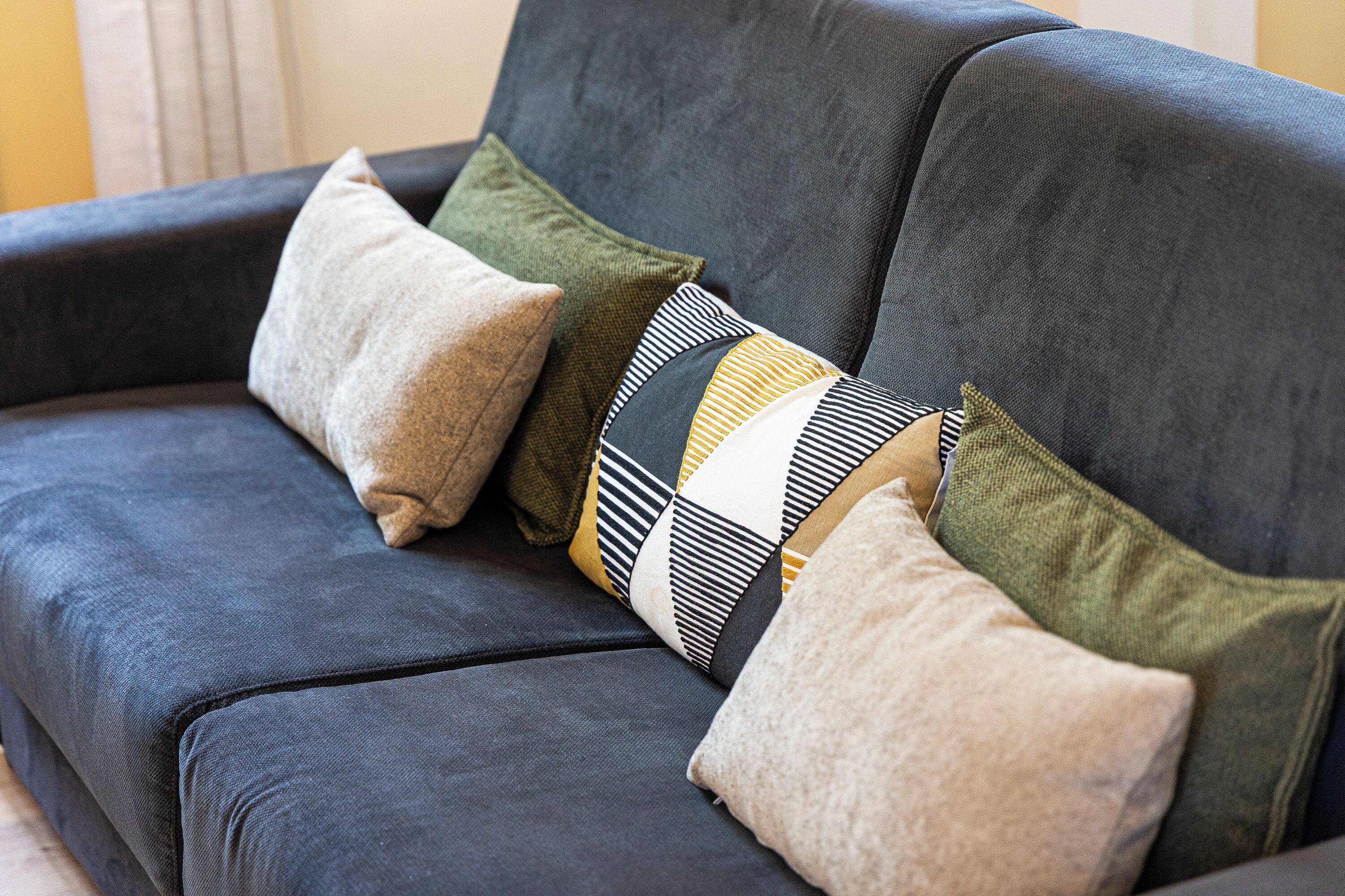 Un canapé gris foncé agrémenté de plusieurs coussins aux motifs et couleurs variés.
