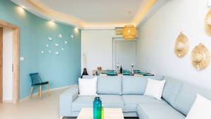 Ein modernes Wohnzimmer mit einem hellblauen Sofa, einem Holztisch und einem türkisfarbenen Sessel.