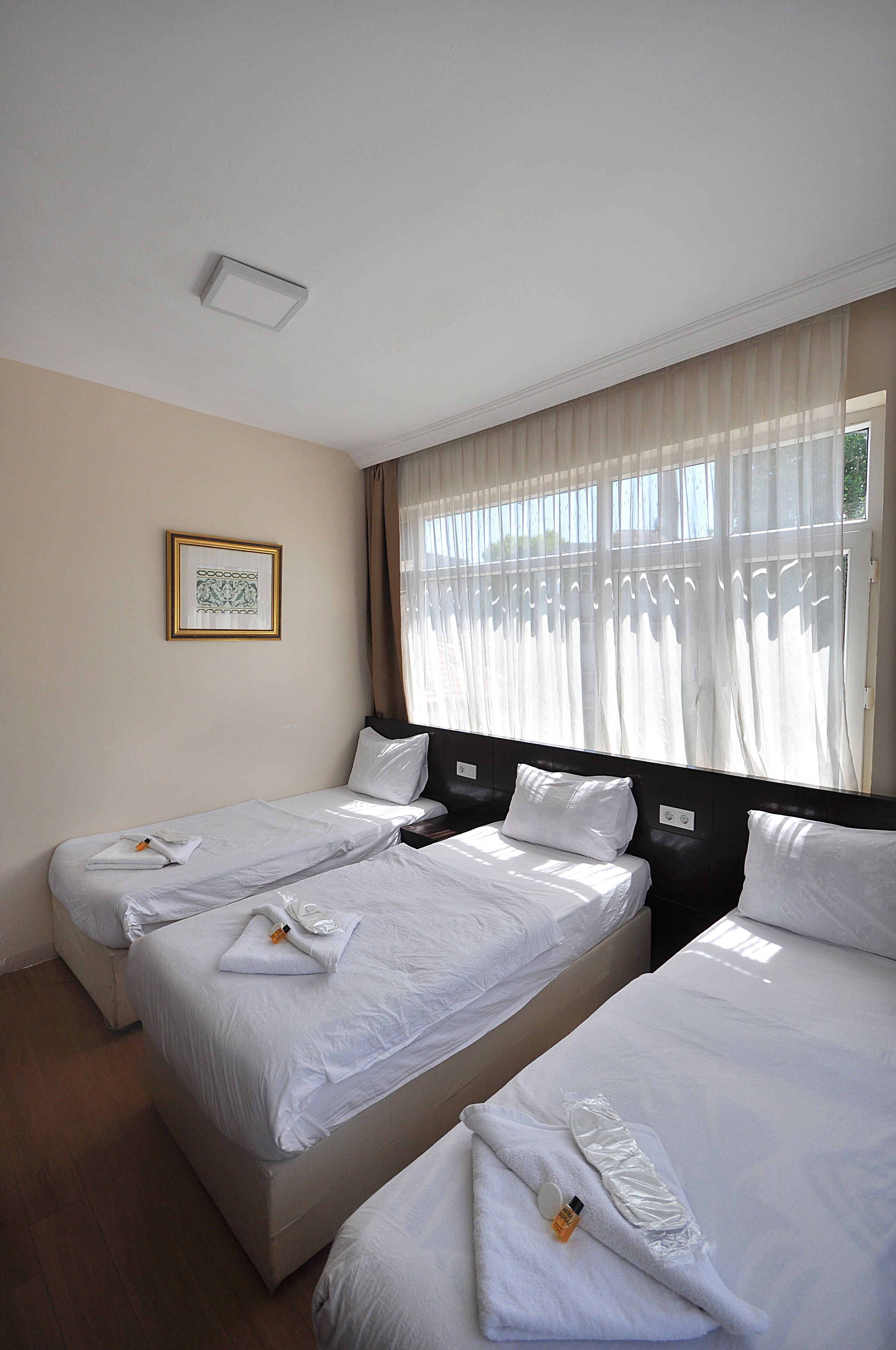 A hotel room with two beds, a framed picture on the wall, and a window with curtains.