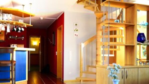 A modern kitchen with wooden cabinets, a bar area, and a staircase leading to an upper level. - Altstadthotel Haßfurt (Hassfurt)