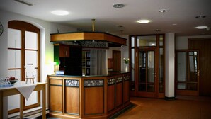 A kitchen with wooden cabinets, a central island, and a window. - Altstadthotel Haßfurt (Hassfurt)