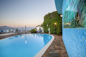 Una piscina con sillas de descanso y vistas al mar.