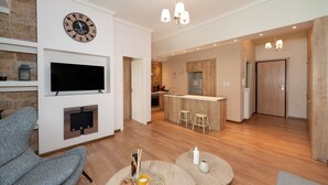 A modern living room with a flat-screen TV, a clock, and a fireplace. - Contemporary Apartment made of Wood and Stone (Athens)