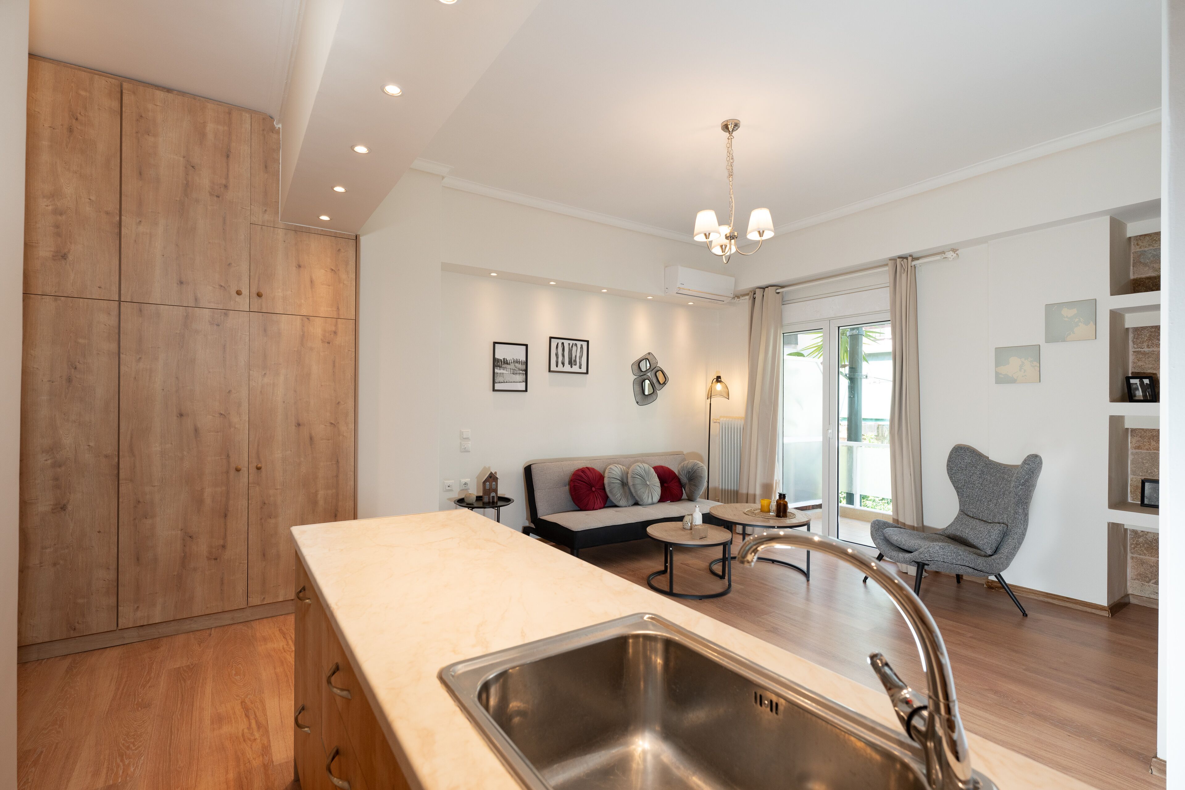 Een moderne keuken met een groot eiland, een inbouw houten kast en een zithoek met een bank en een stoel.