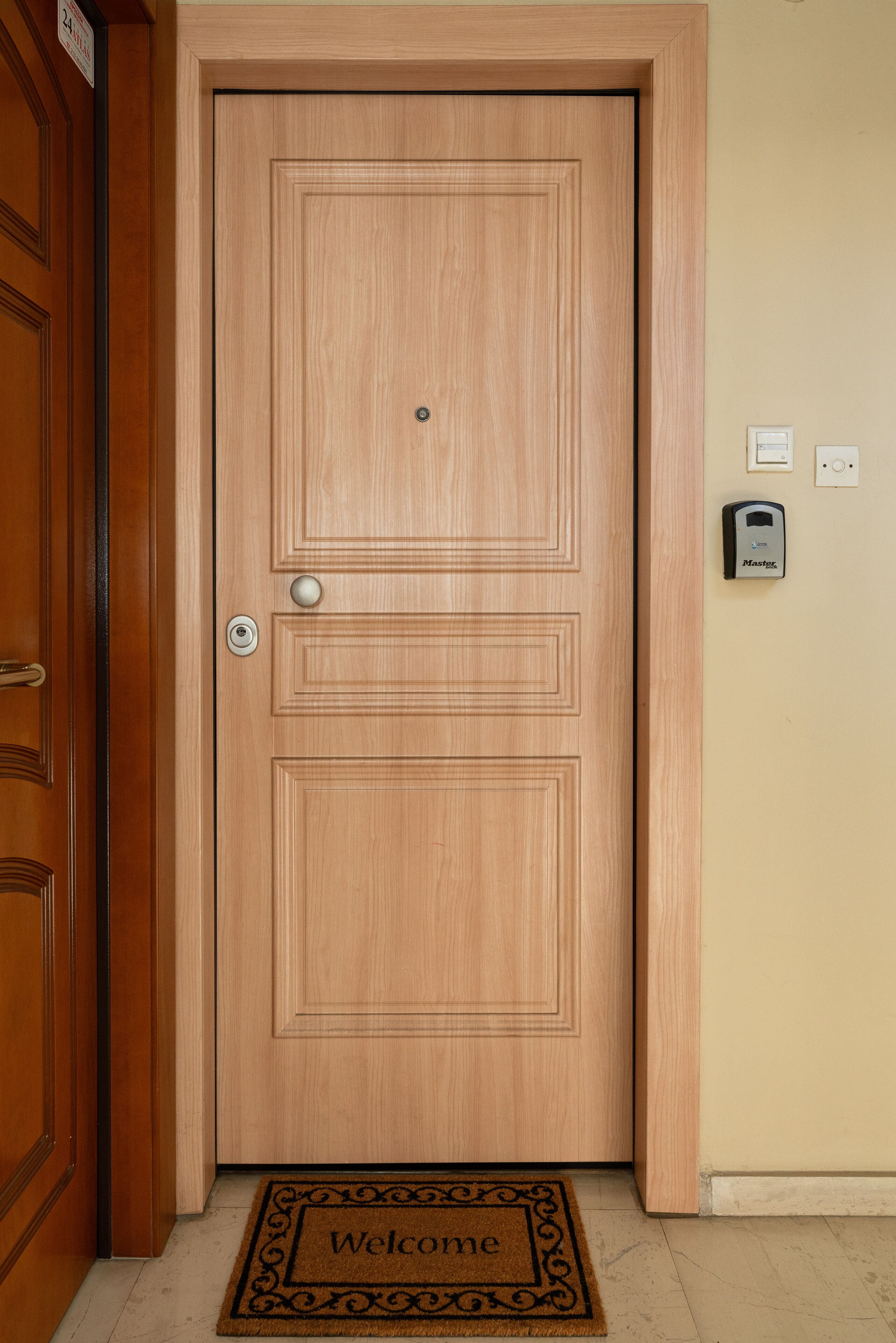 Une porte en bois avec un paillasson sur lequel on peut lire « Bienvenue ».