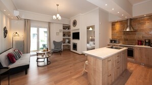 A modern kitchen with a central island, built-in appliances, and a dining area with a sofa and coffee table. - Contemporary Apartment made of Wood and Stone (Athens)