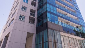 Ein hohes, modernes Gebäude mit Glasfassade und mehreren Balkonen.