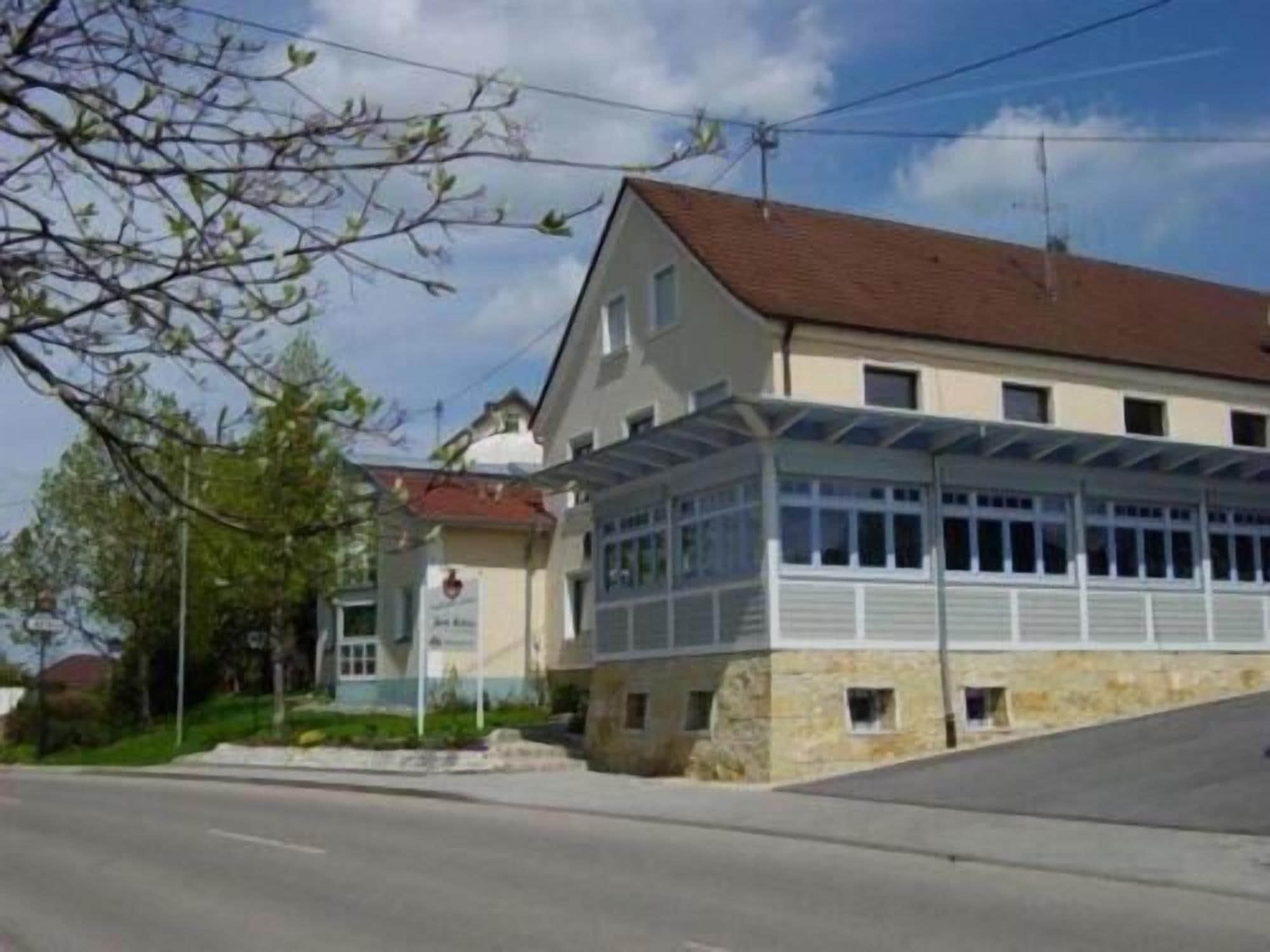 Un bâtiment à deux étages, doté d’un toit en pente, d’un espace d’entrée abrité et d’un petit jardin à l’avant.