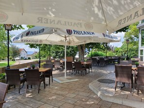 An outdoor patio area with tables and chairs under umbrellas branded with "PAULANER." - Stempfle's Landgasthof Zum Kreuz (Unterschneidheim)