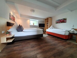 A modern bedroom with a large bed, a smaller bed, a desk, and a TV. - Stempfle's Landgasthof Zum Kreuz (Unterschneidheim)