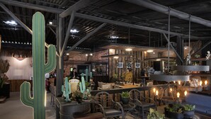 Un interior rústico con vigas a la vista, muebles de madera y una gran escultura de cactus iluminada.