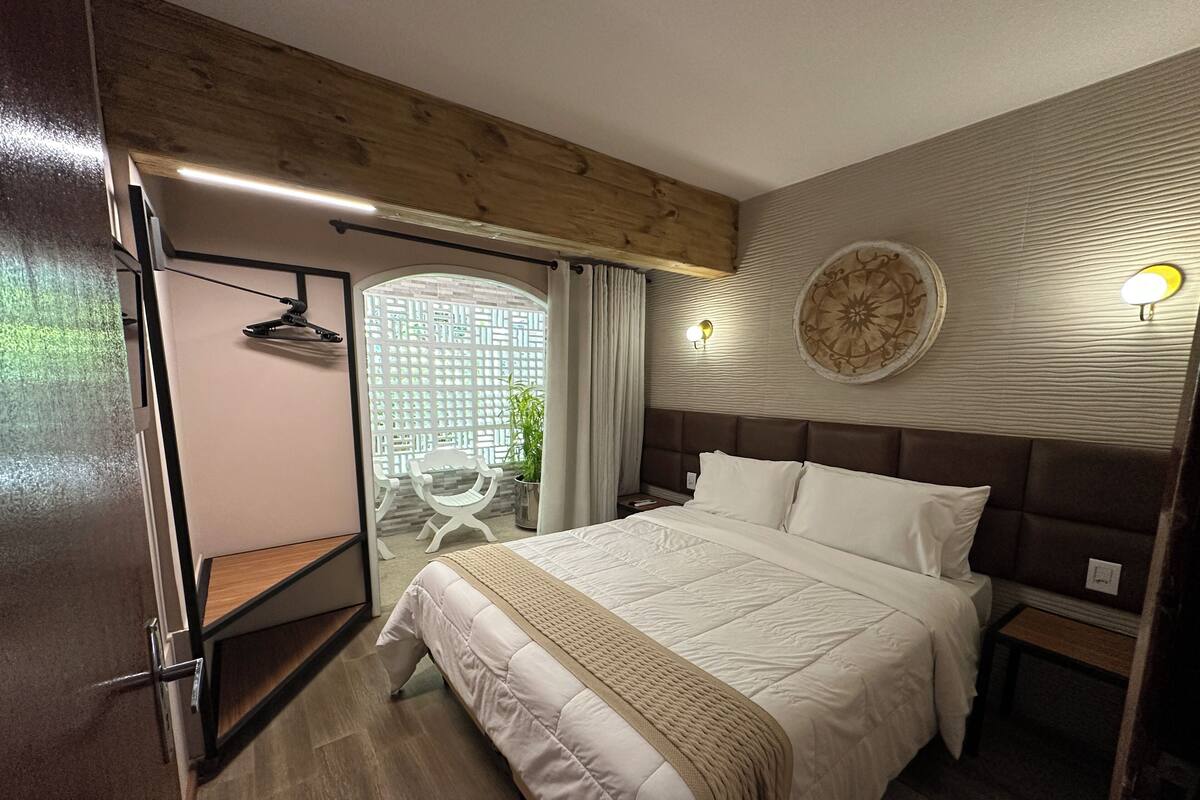 A bedroom with a large bed, wooden ceiling, a wall-mounted light fixture, and a decorative wall plate.