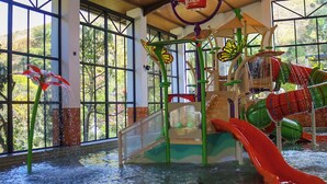 Zona de juegos acuáticos en interior con toboganes y una fuente.