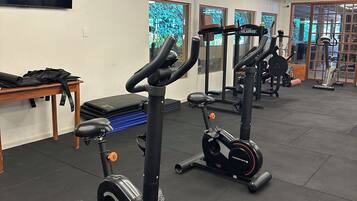 Uma academia com bicicletas ergométricas, um banco e equipamentos de exercícios.