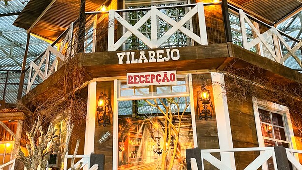 Hotel Vilarejo, con área de recepción, fachada de madera y un balcón.