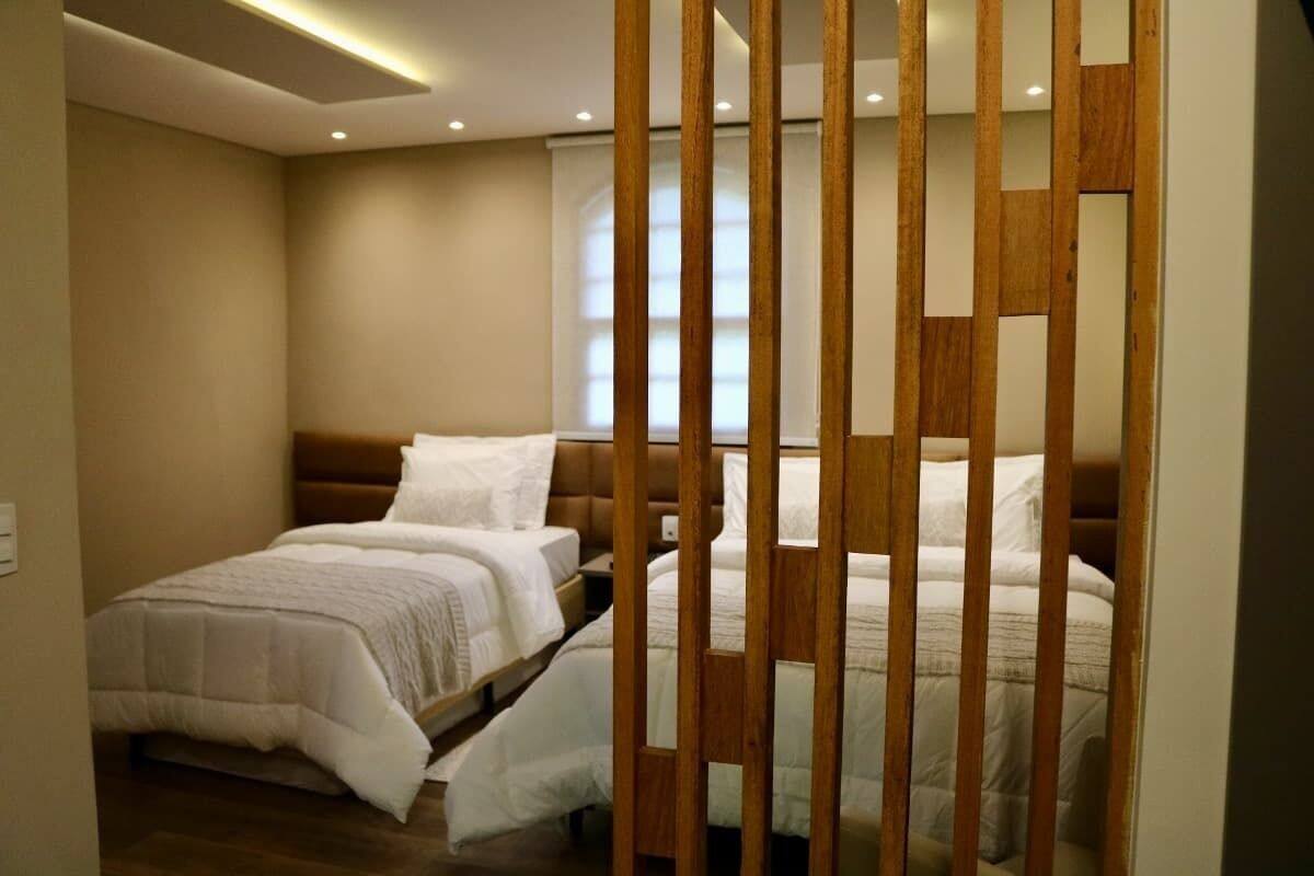 A bedroom with two beds, wooden headboards, and a modern ceiling light fixture.