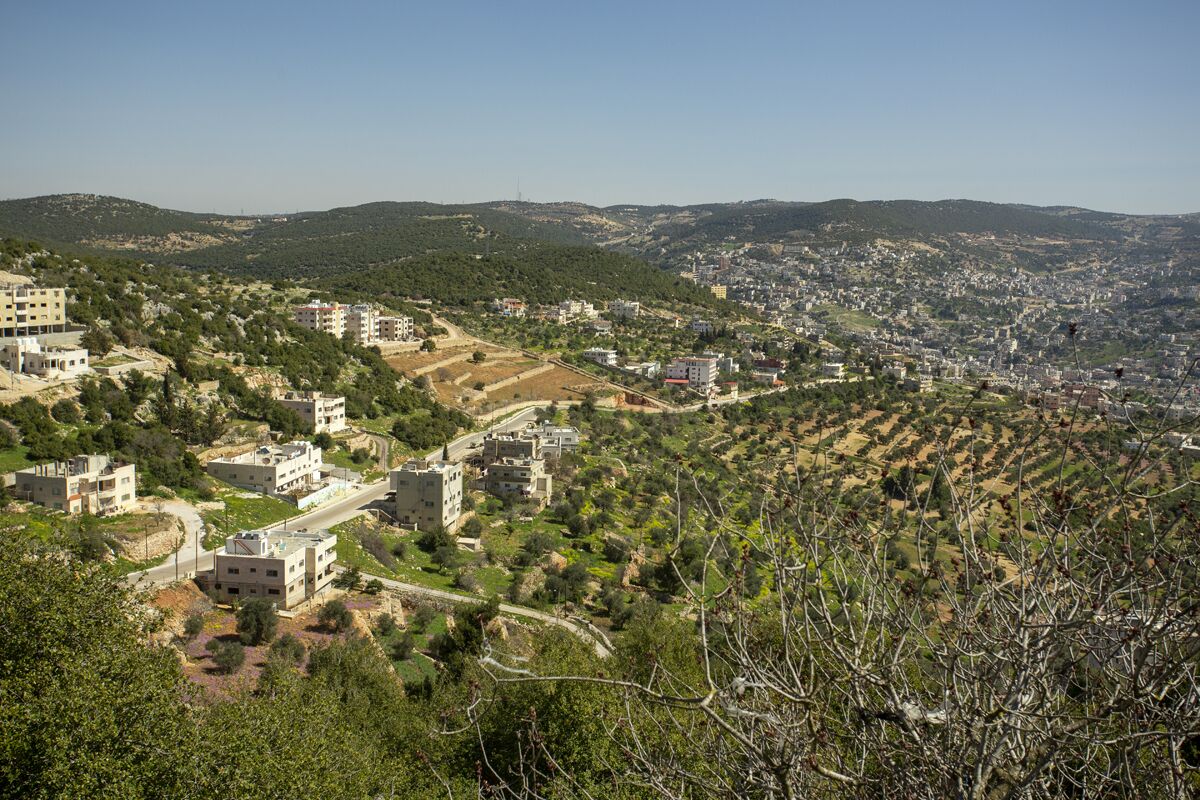 A hillside town with buildings, roads, and greenery.