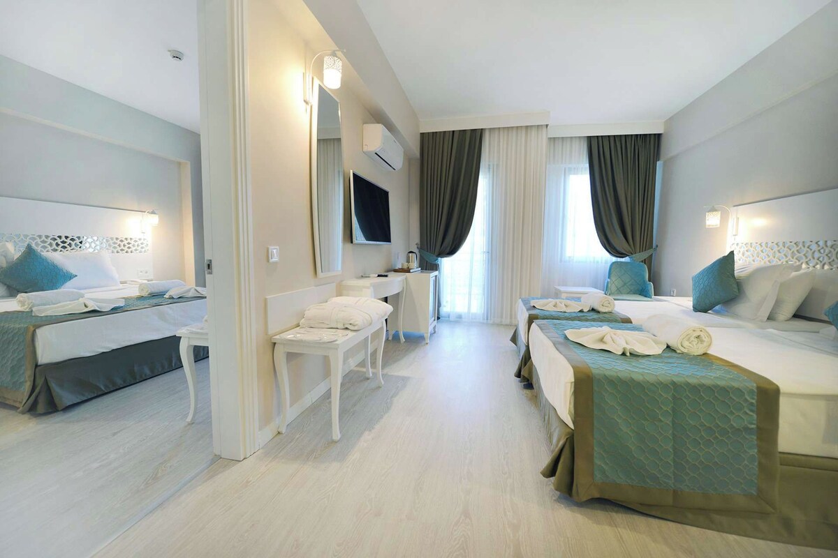 Habitación de hotel con dos camas, un escritorio, una silla y un televisor.