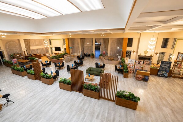 A spacious hotel lobby with multiple seating areas, including sofas and tables, and a central decorative wooden partition. - Adempira Termal & Spa Hotel (Denizli)