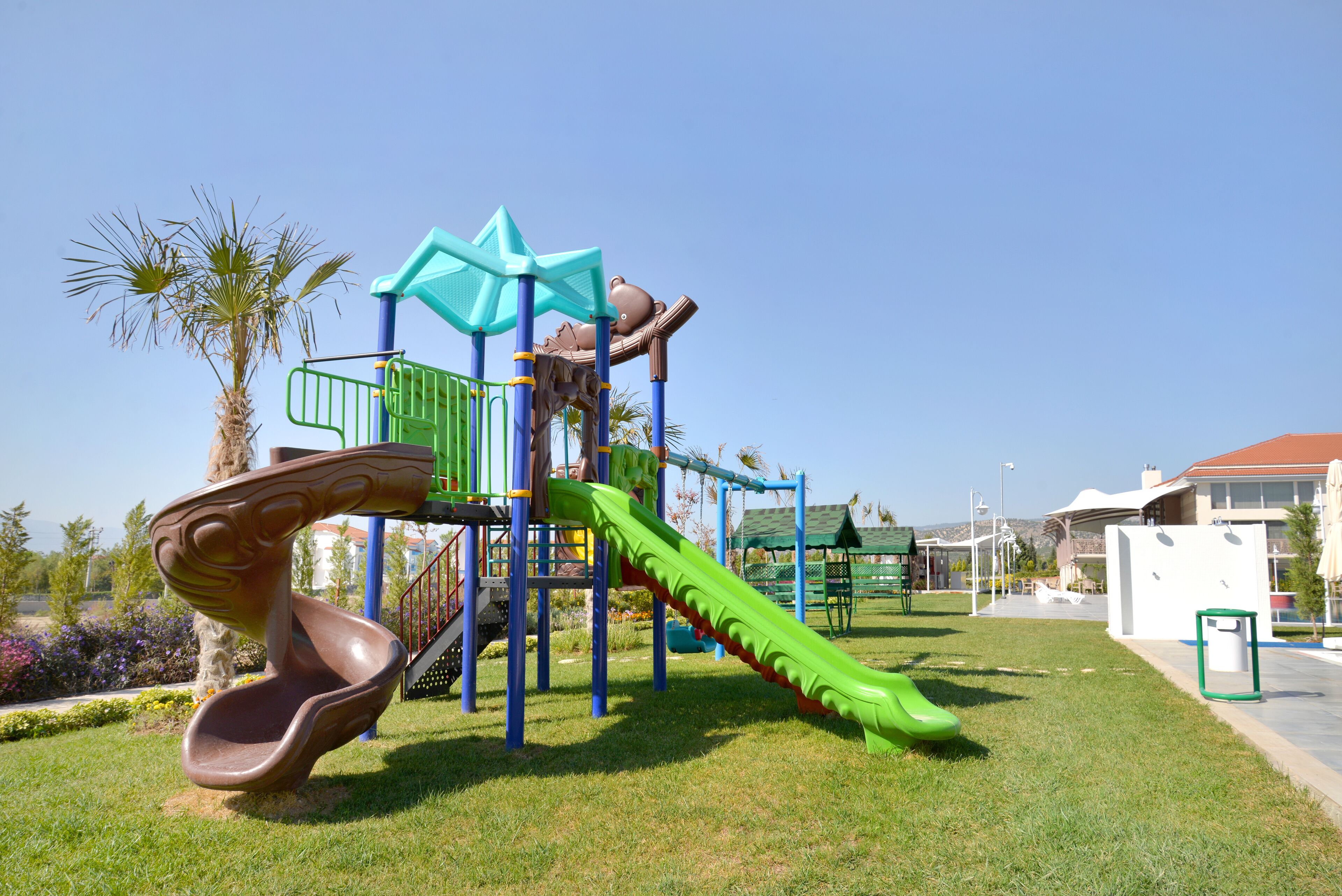Un parque infantil con tobogán, estructuras para escalar y una zona verde.