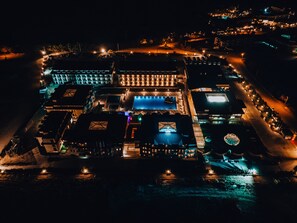 An aerial view of a hotel with multiple buildings, a swimming pool, and a well-lit parking area. - Adempira Termal & Spa Hotel (Denizli)