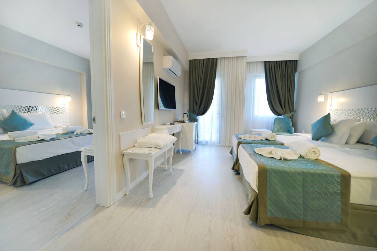 Una habitación de hotel con dos camas, un escritorio y un espejo.
