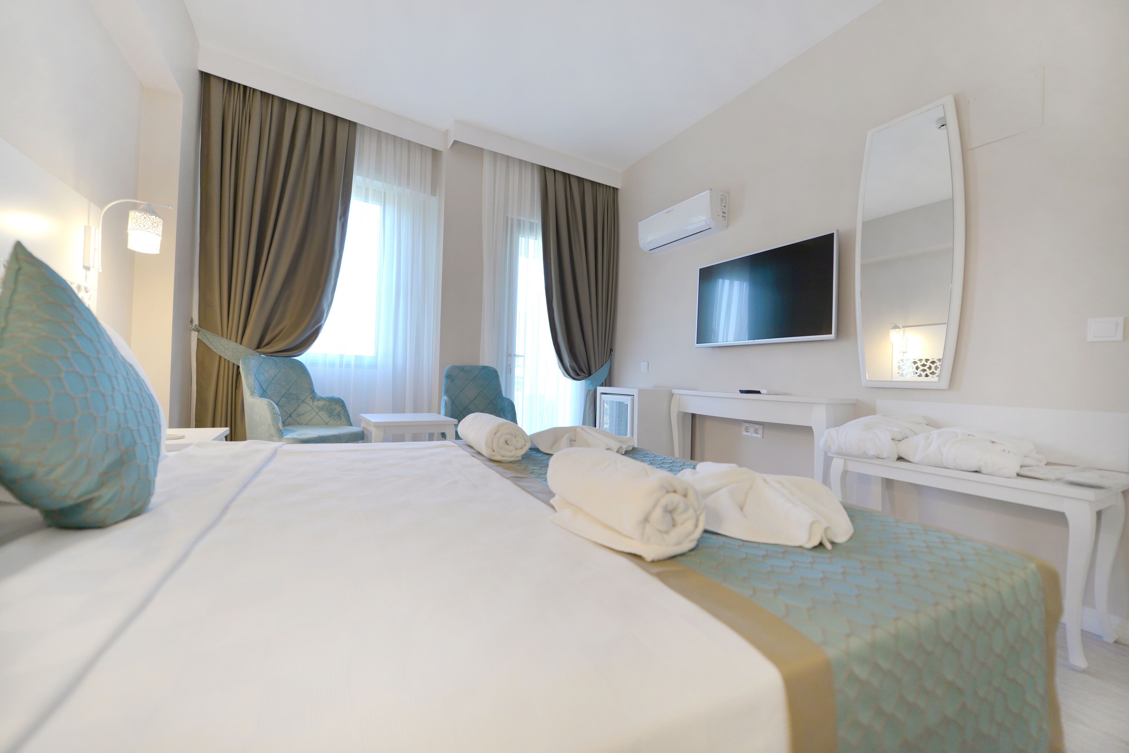 Una habitación de hotel con una cama grande, un escritorio, una silla, un televisor y un espejo.