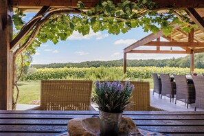Un espacio de estar al aire libre techado con muebles de mimbre y una planta en maceta.