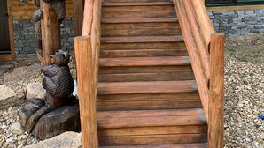A wooden staircase leading to a cabin with a rustic design, surrounded by natural elements. - Gorgeous 4BR Log Home Near Storyland & N. Conway. AC, Large Deck, Dog friendly (Bartlett)