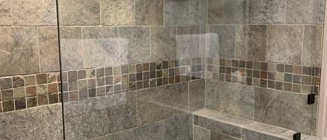 A bathroom with a glass-enclosed shower area, tiled walls, and a white countertop.