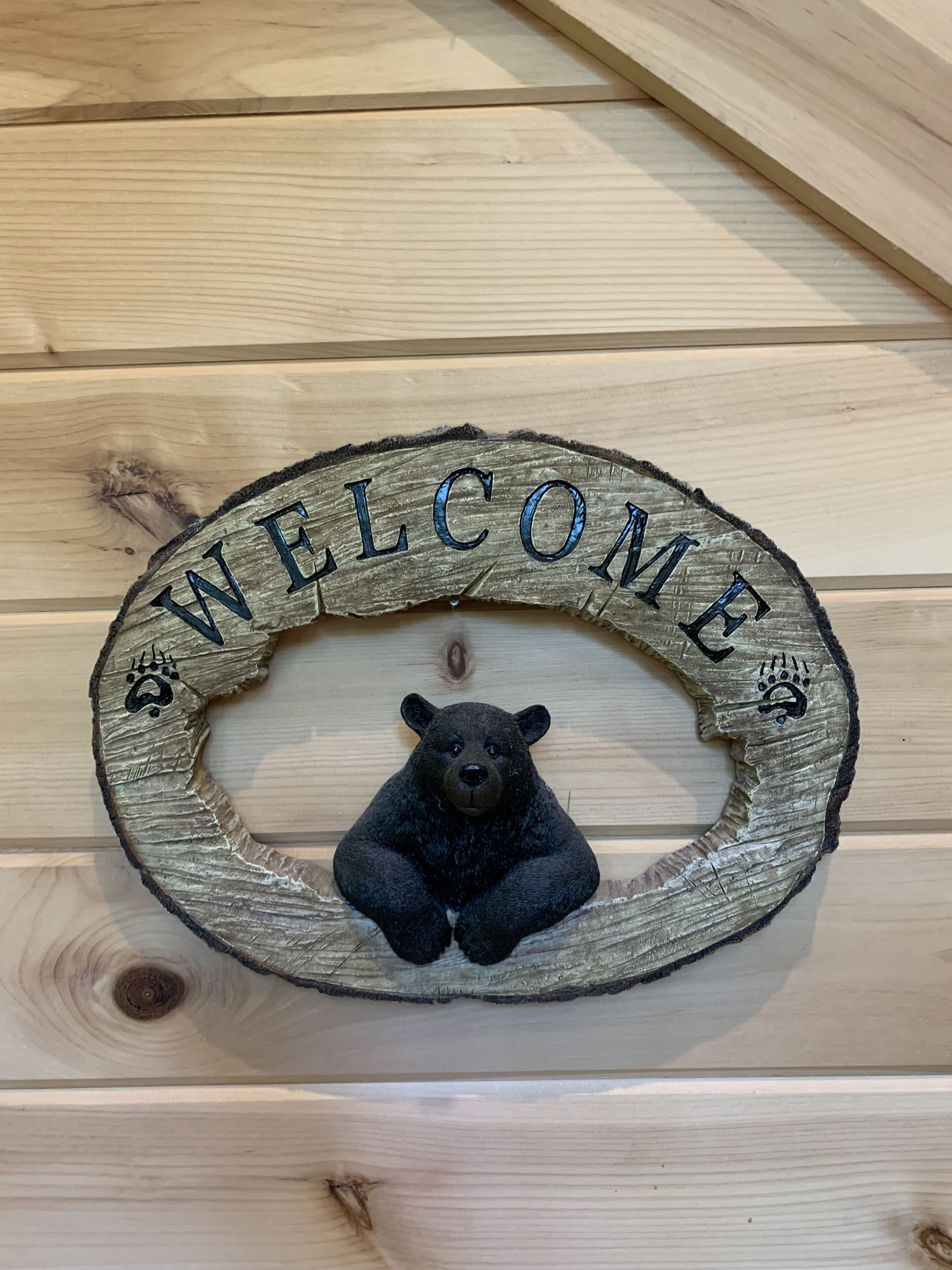 Un letrero de bienvenida de madera con una figura de oso y huellas de patas.